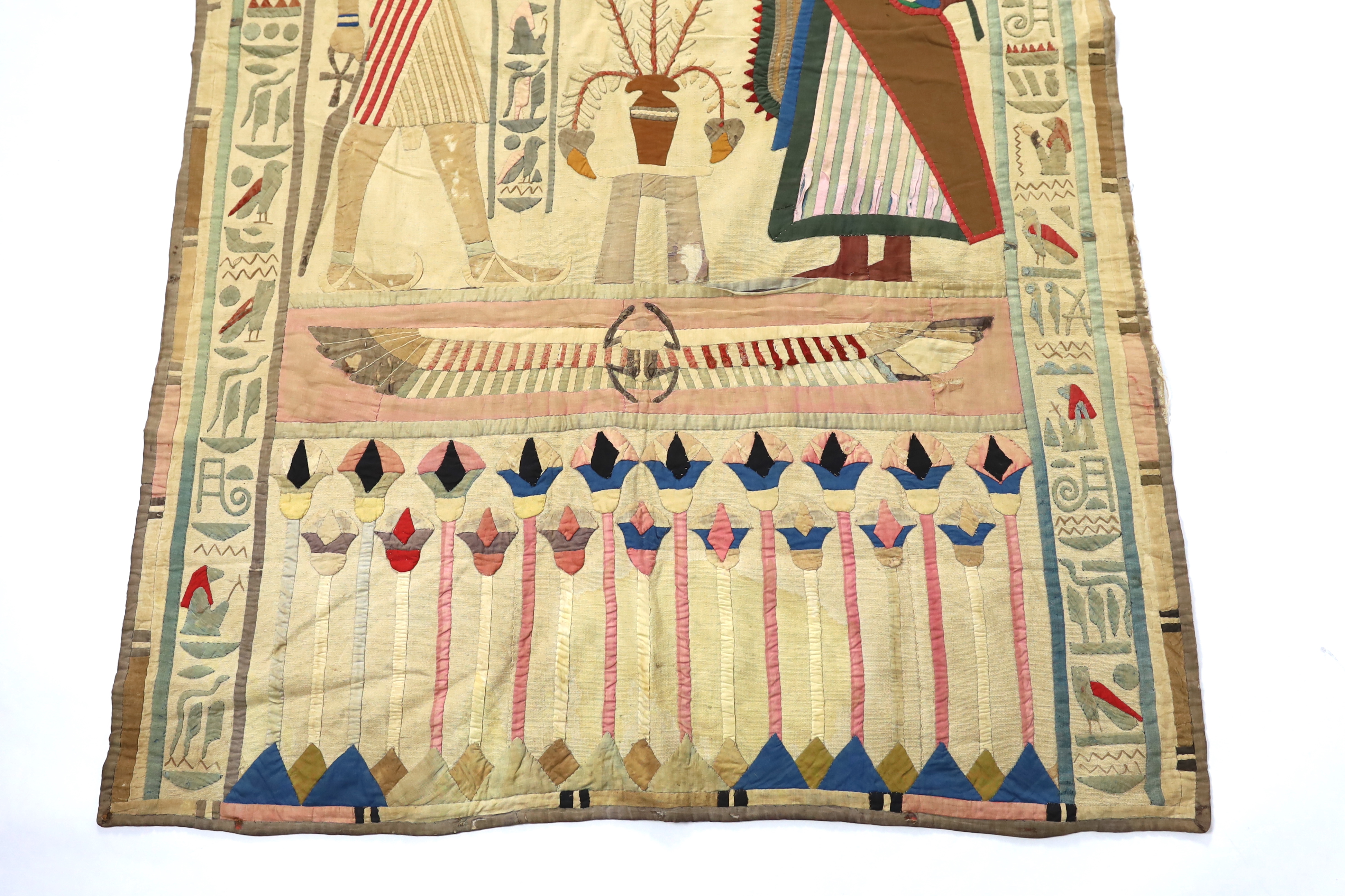 A 1930’s large Egyptian appliqué wall hanging, depicting Wadjet, (Goddess and protector of Kings) and Amun (God of wind) surrounded by hieroglyphic decorative symbols, 134cm wide x 268cm long